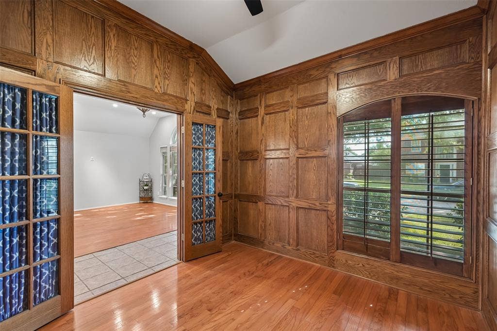 3837 Pine Valley Drive, Plano, TX 75025 Custom wood paneling, wood-finish flooring, vaulted ceiling, arched window with wood trim, and glass-paneled double doors