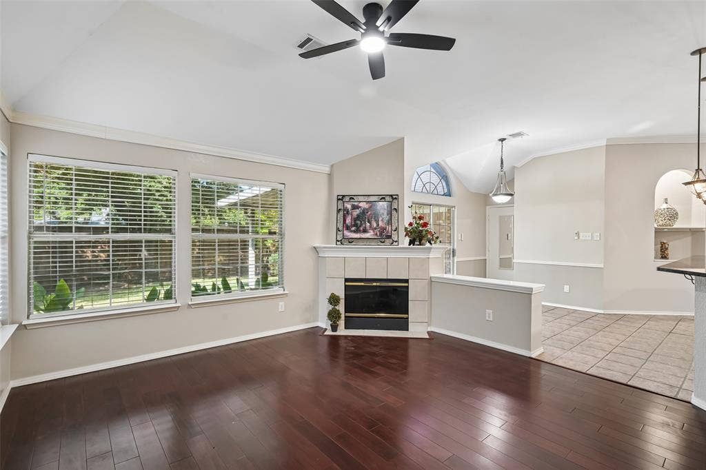 3837 Pine Valley Drive, Plano, TX 75025 Vaulted ceilings, wood-finish flooring, corner fireplace with tile surround, large dual-pane windows, and arched architectural niche