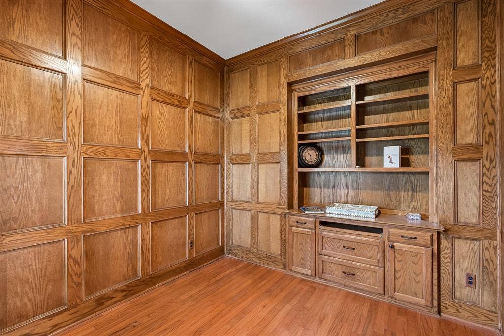 3837 Pine Valley Drive, Plano, TX 75025 Custom wood-paneled walls, built-in floor-to-ceiling shelving, integrated cabinetry with drawers, and wood-finish flooring