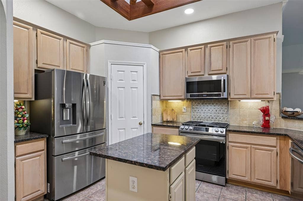 3837 Pine Valley Drive, Plano, TX 75025 Kitchen featuring natural wood cabinetry, granite countertops, central island, stainless steel appliance suite, large pantry and tiled backsplash