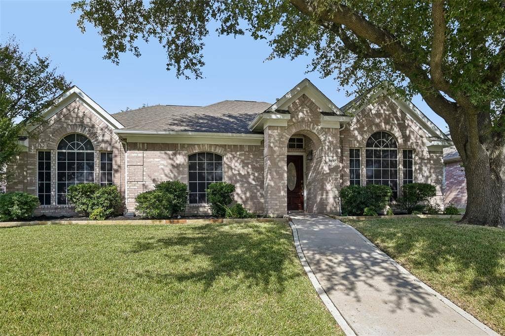 3837 Pine Valley Drive, Plano, TX 75025 Brick exterior featuring an arched entryway, gabled rooflines, decorative transom windows, and a concrete walkway