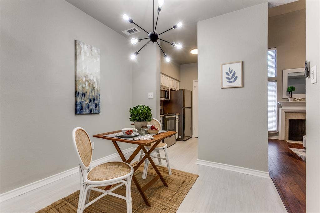 Dining area featuring light-toned flooring, neutral wall paint, and a multi-arm, modern overhead light fixture