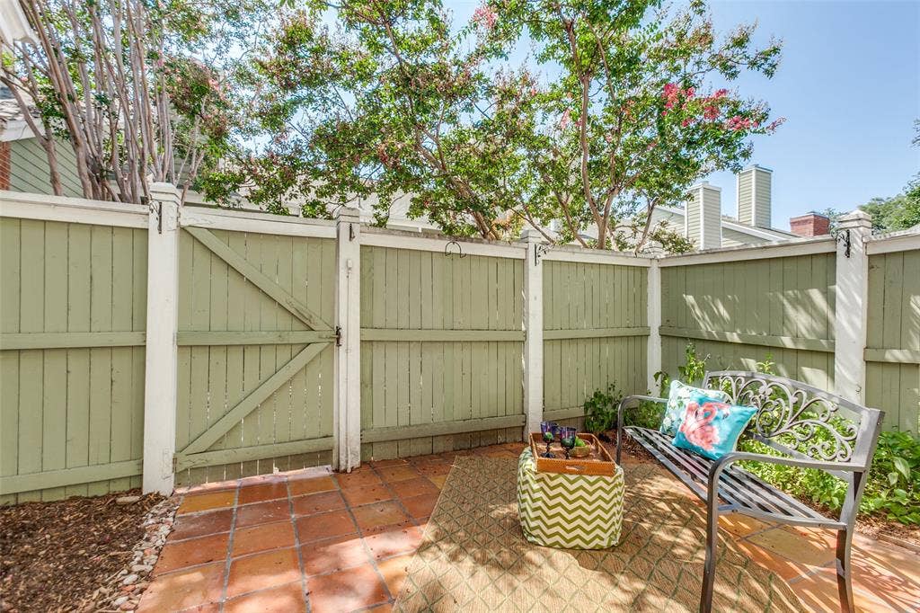 Enclosed courtyard featuring terracotta tile flooring, painted wood fencing, and a gated entrance