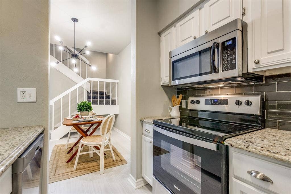 Kitchen featuring white cabinetry, stone-finish countertops, subway tile backsplash, and stainless steel appliances