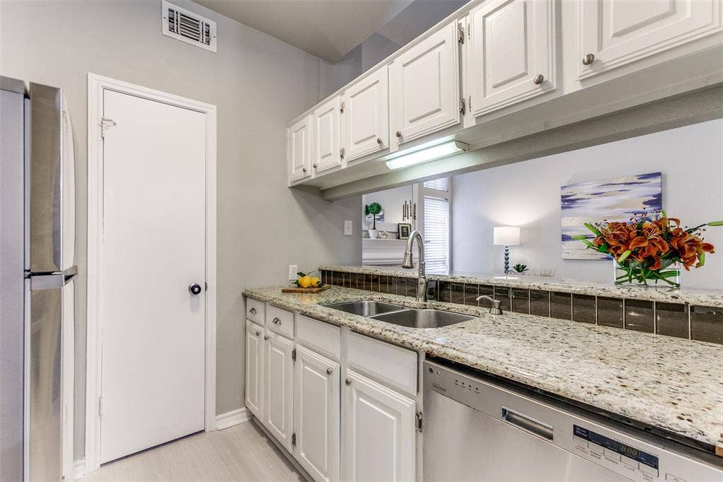 Kitchen featuring white cabinetry, light-toned stone-finish countertops, stainless steel undermount sink with arched pull-down faucet, and built-in stainless steel dishwasher