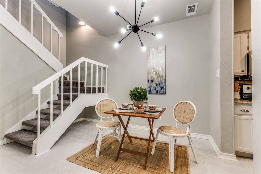 Modern sputnik-style chandelier, staircase with white railing, and neutral-tone flooring