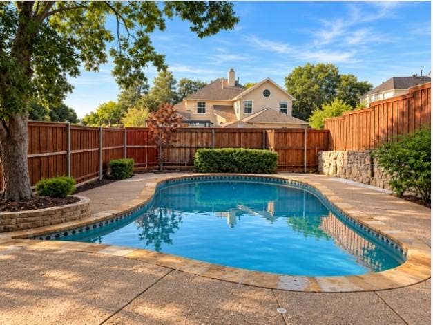 In-ground swimming pool with stone coping, and full-perimeter wood privacy fencing.
