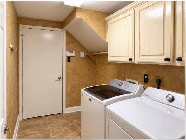 Utility area featuring wood-finish cabinetry, tile flooring, and a wall-mounted hanging rod. Access to garage.