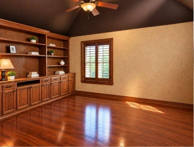 Custom floor-to-ceiling wood cabinetry with integrated shelving and base storage, hardwood flooring, vaulted ceiling, French doors, and wooden plantation shutters.