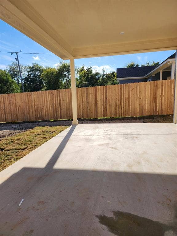 Covered concrete patio featuring a vertical wood privacy fence and structural support column