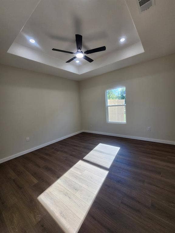 Tray ceiling featuring recessed lighting and a central ceiling fan, complemented by wood-finish flooring