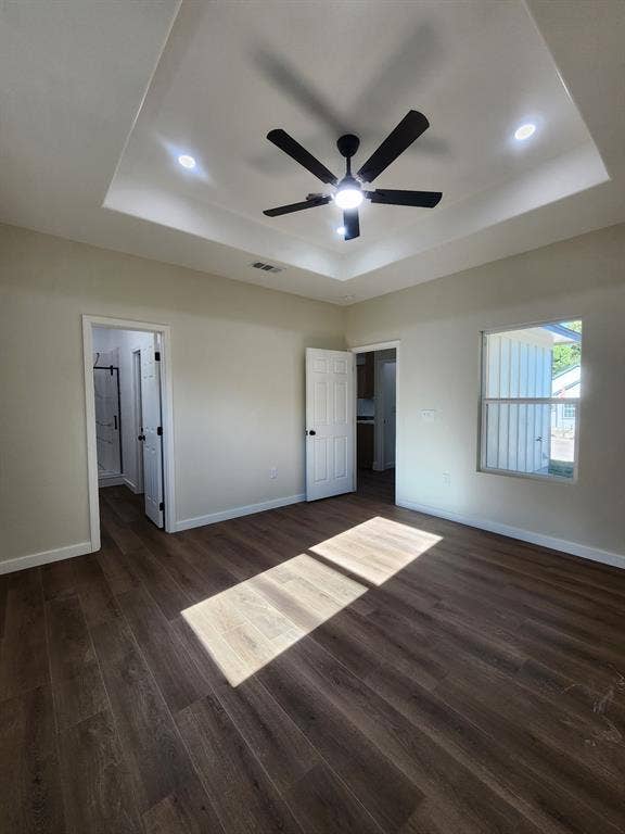 Tray ceiling featuring recessed lighting and a central ceiling fan, paired with wood-finish flooring