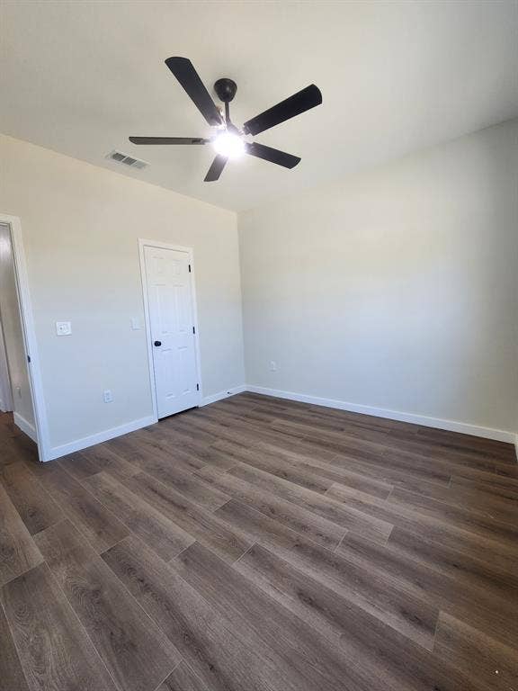 Room featuring wood-finish flooring, a five-blade ceiling fan, and a six-panel door