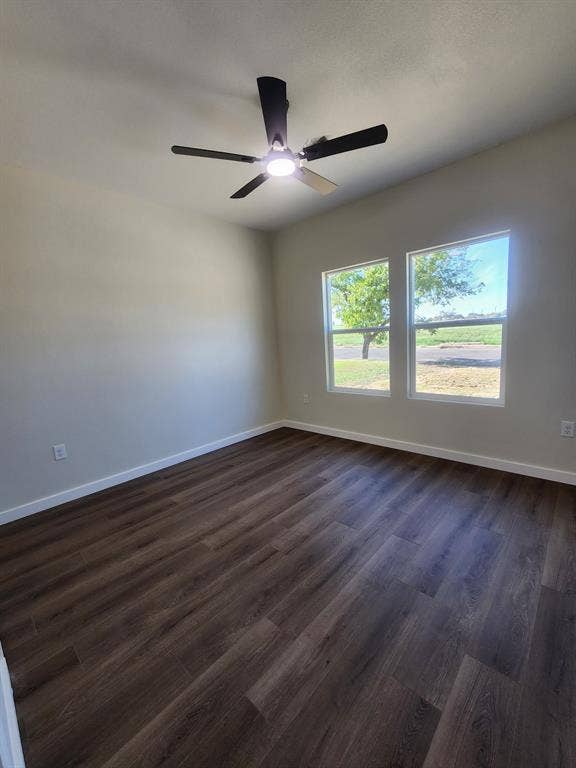 Interior space featuring wood-finish flooring, neutral wall paint, double-pane windows, and a matte black ceiling fan with an integrated light fixture