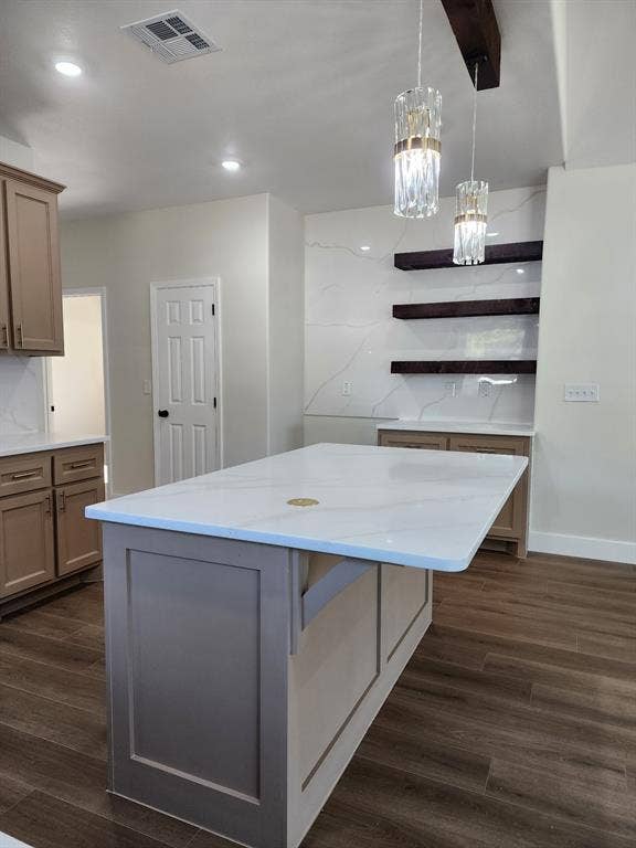 Kitchen featuring a central island with a solid surface countertop, wood-finish flooring, custom shaker-style cabinetry, floating shelves, and crystal pendant lighting