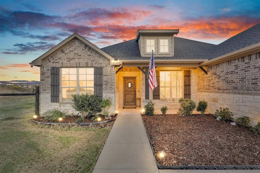 9880 County Road 466, Princeton, TX 75407 Brick and stone exterior featuring dark wood-finish shutters, a covered entryway, and a dormer window