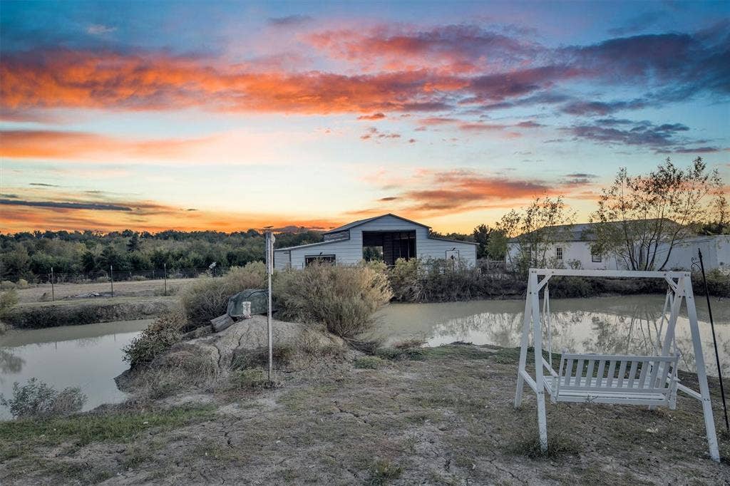 9880 County Road 466, Princeton, TX 75407 Rural property featuring a pond, outbuilding, and expansive horizon at sunset