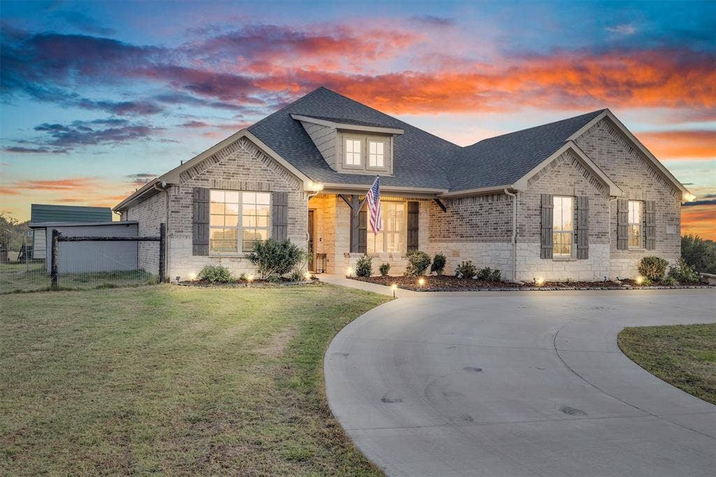9880 County Road 466, Princeton, TX 75407 Multi-gabled brick and stone facade featuring decorative window shutters, a covered entryway with timber support beams, and a curved concrete driveway