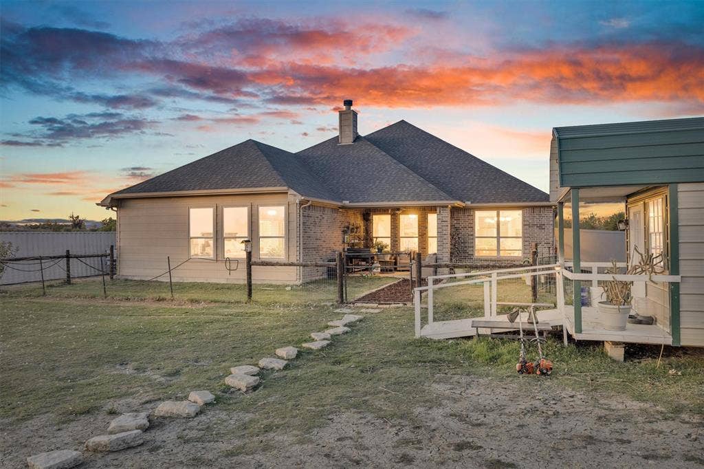 9880 County Road 466, Princeton, TX 75407 Single-story residence featuring a brick and siding exterior, expansive rear lawn, stone paver path, and detached auxiliary structure with a ramped entryway