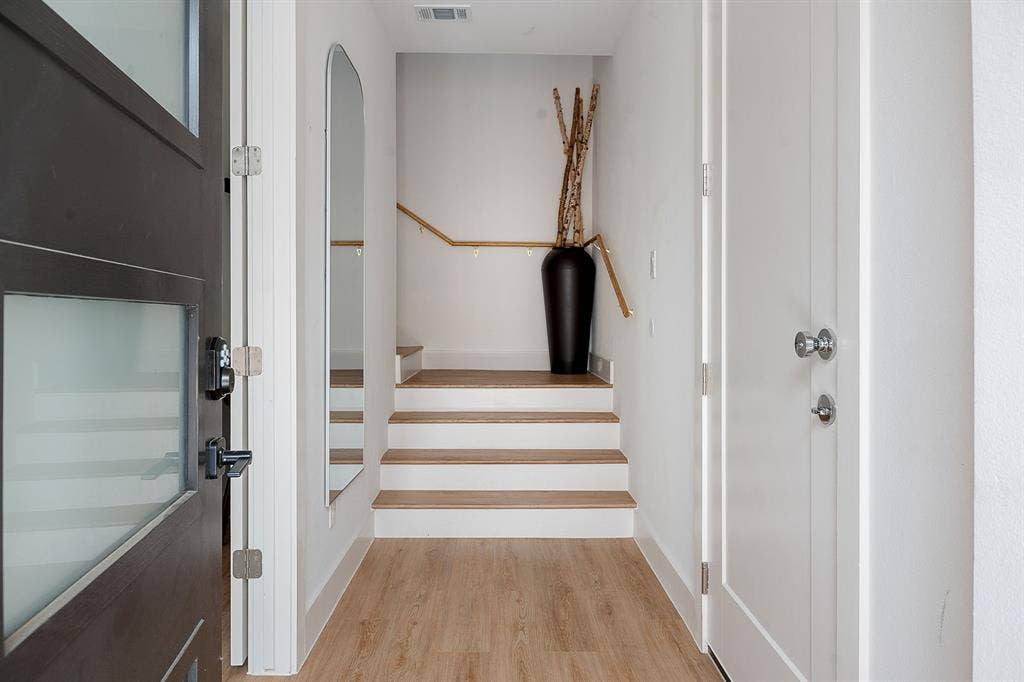 Entryway featuring a dark-finish door with frosted glass panels, wood-finish flooring, and a staircase with a wooden handrail