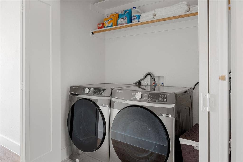 Laundry alcove featuring stainless steel front-load appliances and overhead built-in shelving