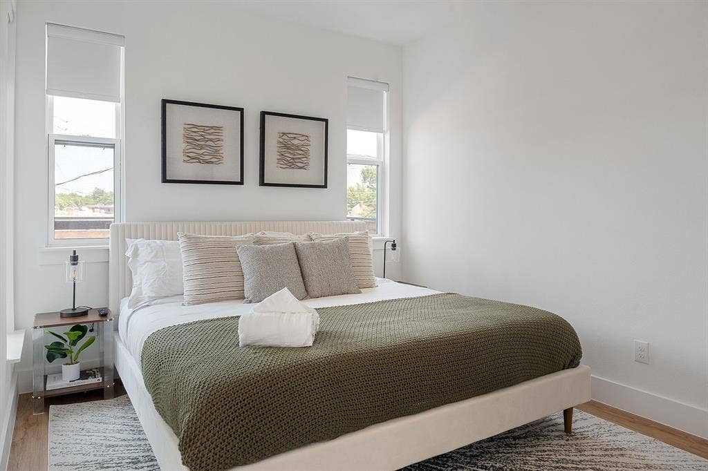 Room featuring white walls, wood-finish flooring, and dual windows with fitted shades