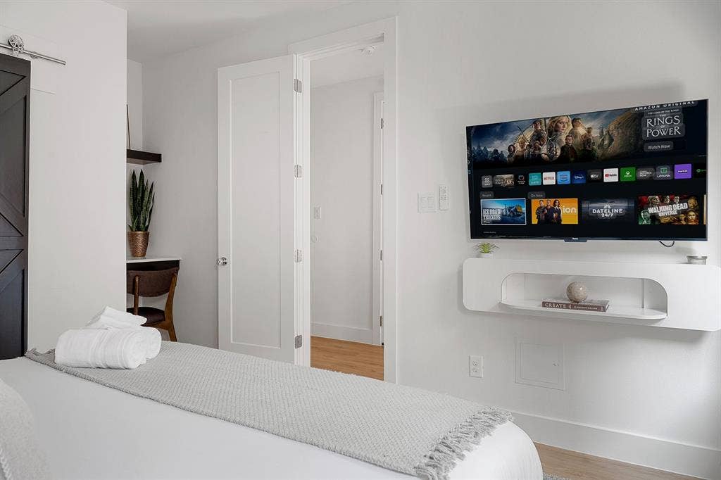 Interior featuring a dark-finish sliding barn door, wall-mounted white floating media console with open shelving, integrated built-in desk area with overhead shelving, and multi-panel shaker-style interior door