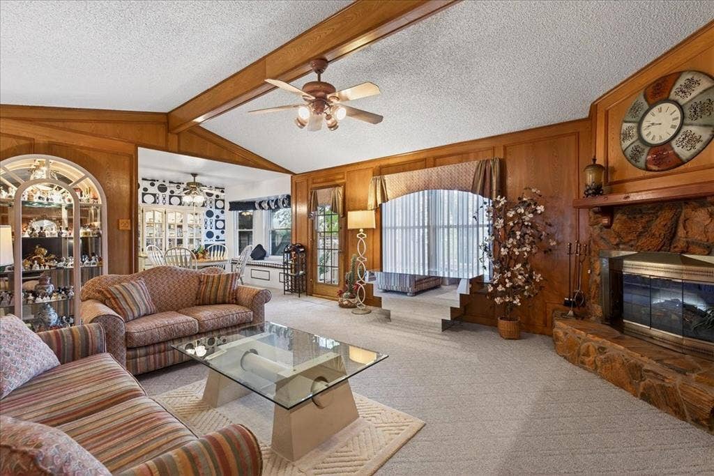 10118 Lakeview Street, Payne Springs, TX 75156 Vaulted ceilings featuring exposed wooden beams, natural stone fireplace with a wooden mantel, wood-paneled walls, and built-in arched display cabinetry