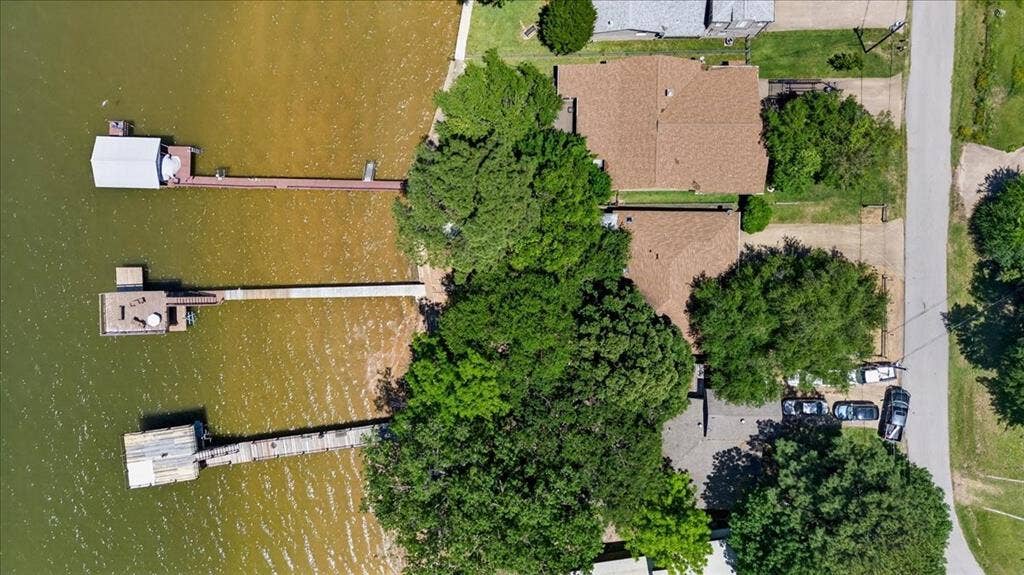 10118 Lakeview Street, Payne Springs, TX 75156 Aerial perspective of waterfront property featuring three private docks, extensive shoreline, mature trees, and paved surface parking