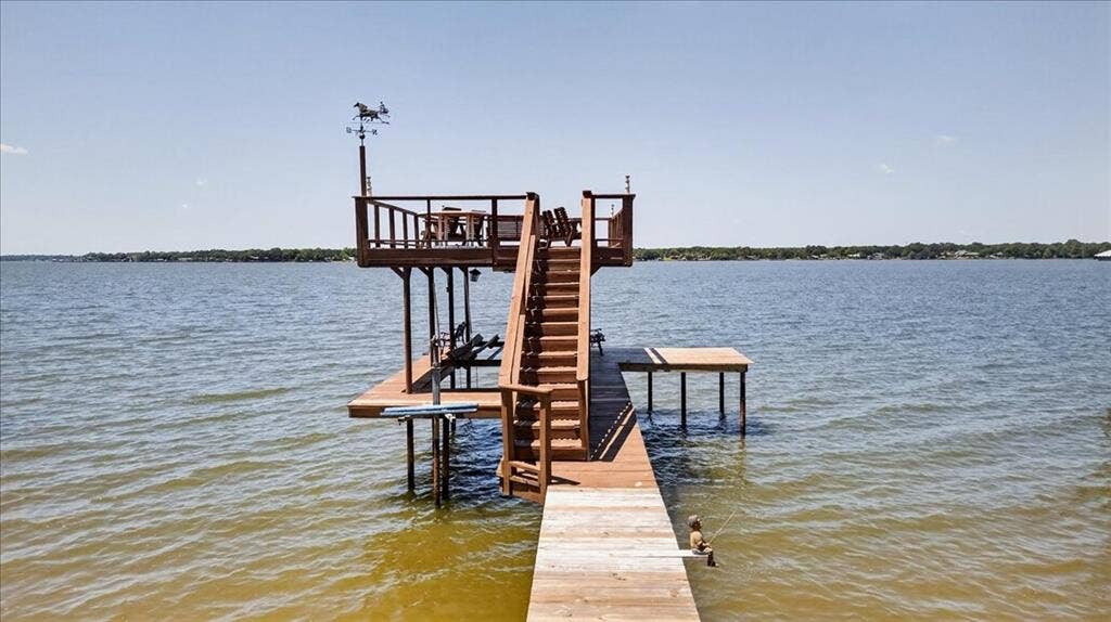 10118 Lakeview Street, Payne Springs, TX 75156 Multi-level wooden dock featuring an upper observation deck, staircase with railings, boat lift, and metal weather vane