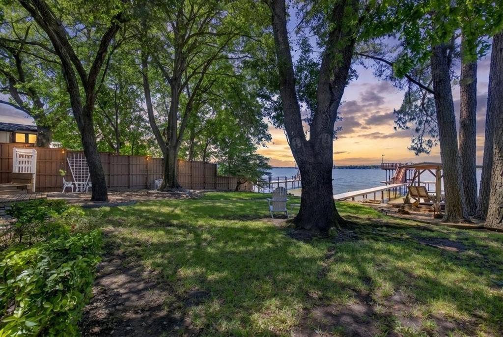 10118 Lakeview Street, Payne Springs, TX 75156 Lakeside grounds featuring mature trees, a wooden privacy fence, and a private dock