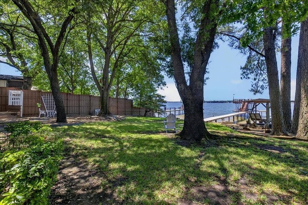 10118 Lakeview Street, Payne Springs, TX 75156 Waterfront property featuring mature trees, a private dock, and a wood privacy fence