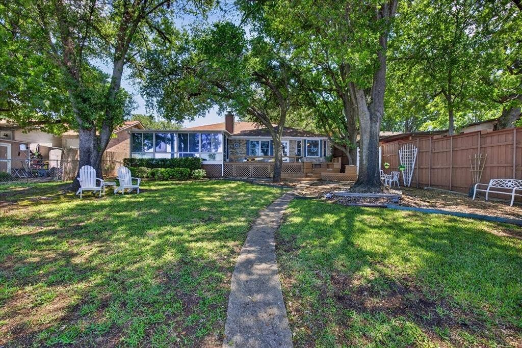 10118 Lakeview Street, Payne Springs, TX 75156 Expansive backyard featuring a stone-clad exterior, a multi-pane sunroom, mature oak trees, and a wooden privacy fence