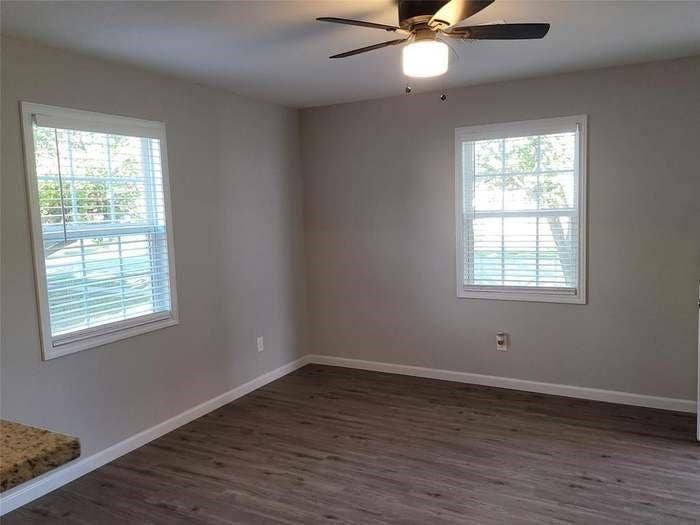 Room featuring wood-finish flooring, dual windows with fitted blinds, and a ceiling-mounted light fixture