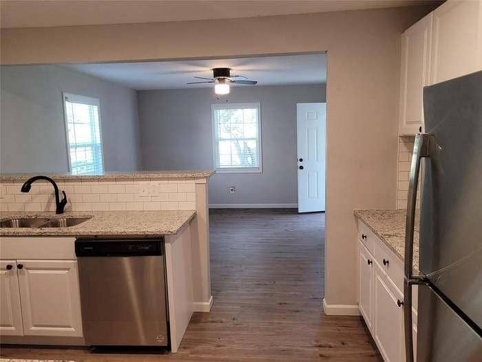 Kitchen featuring white shaker cabinetry, stone-patterned countertops, white subway tile backsplash, and stainless steel appliances