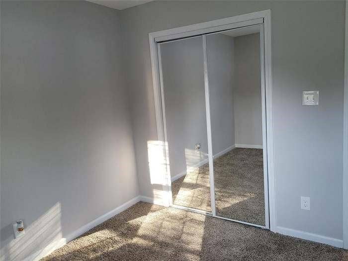 Room featuring neutral wall paint, wall-to-wall carpeting, and floor-to-ceiling sliding mirror closet doors