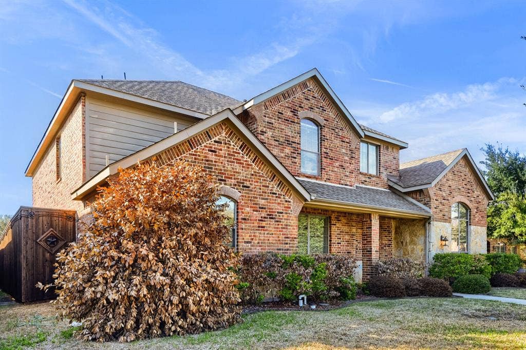 7013 Salem Court, Rowlett, TX 75089 Two-story exterior featuring multi-gabled rooflines, red brick and stone veneer masonry, and arched window detailing