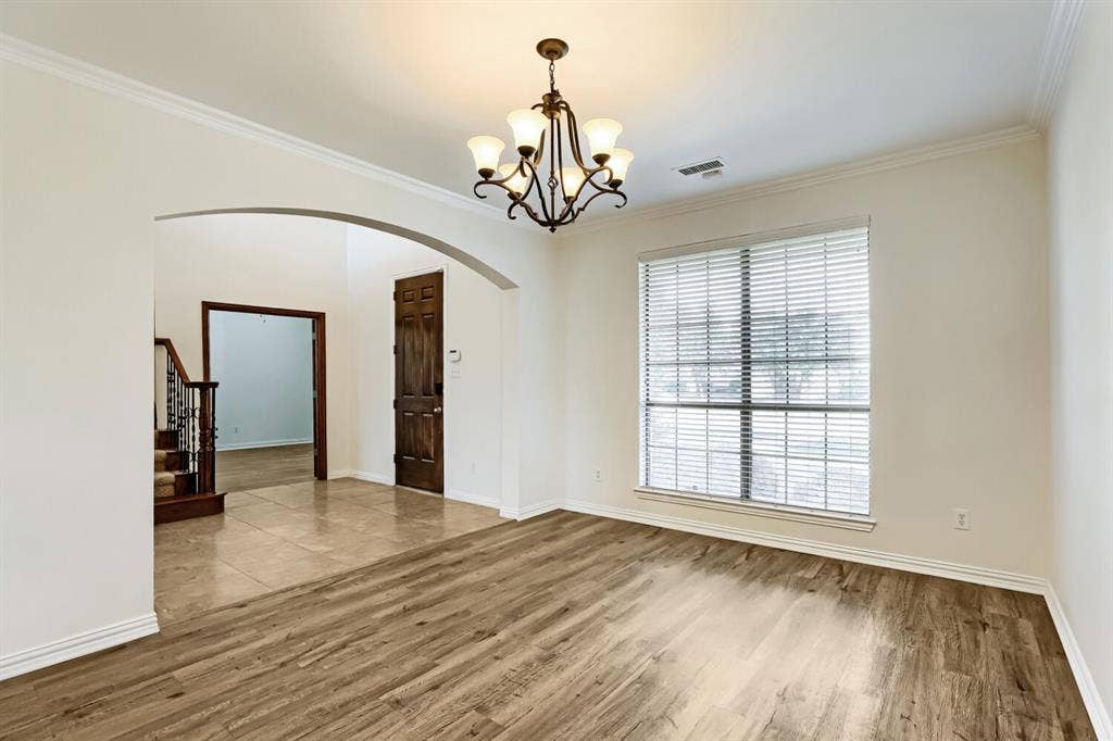 7013 Salem Court, Rowlett, TX 75089 Room featuring wood-finish flooring, a metal multi-light chandelier, an arched architectural opening, and a large multi-pane window