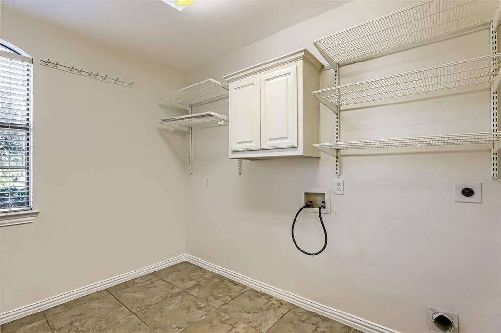 7013 Salem Court, Rowlett, TX 75089 Utility area featuring tile flooring, white shaker-style wall cabinetry, adjustable wire shelving, and an integrated window with horizontal blinds