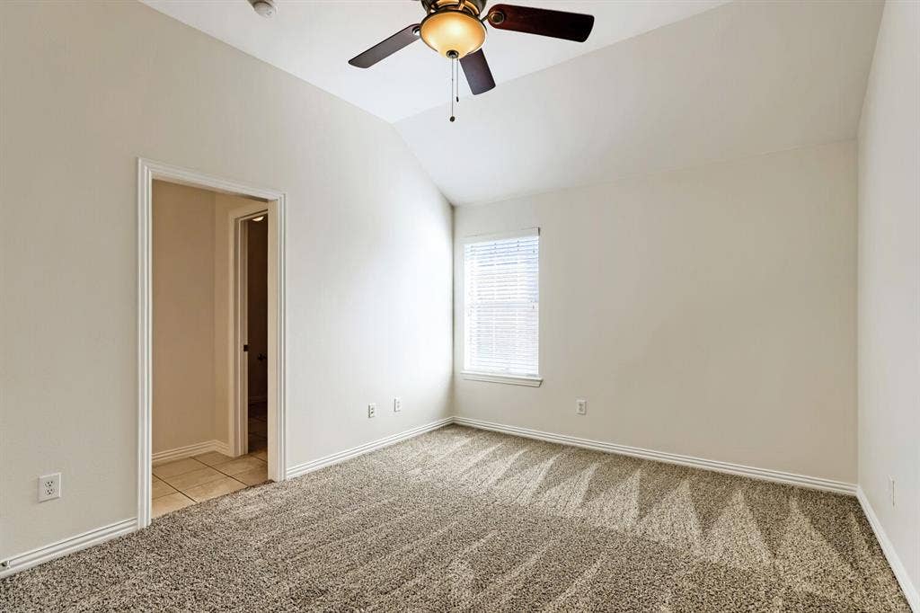 7013 Salem Court, Rowlett, TX 75089 Vaulted ceiling featuring a ceiling fan with integrated lighting, wall-to-wall carpeting, and a single-window configuration