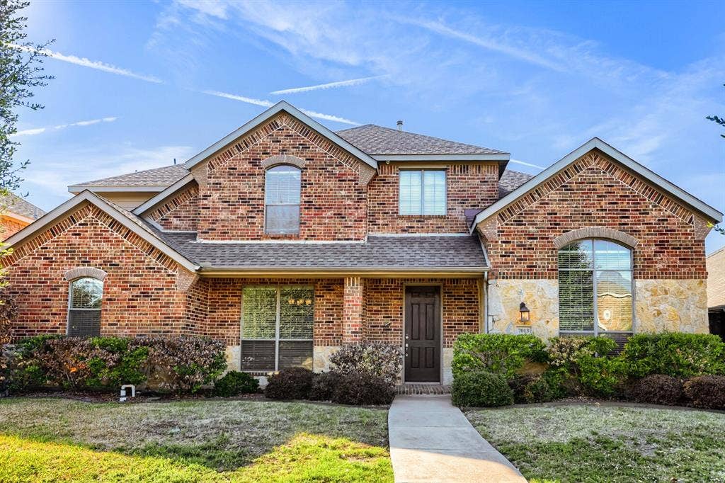 7013 Salem Court, Rowlett, TX 75089 Multi-gabled brick and stone exterior featuring an arched entryway, multiple arched windows, and a concrete walkway