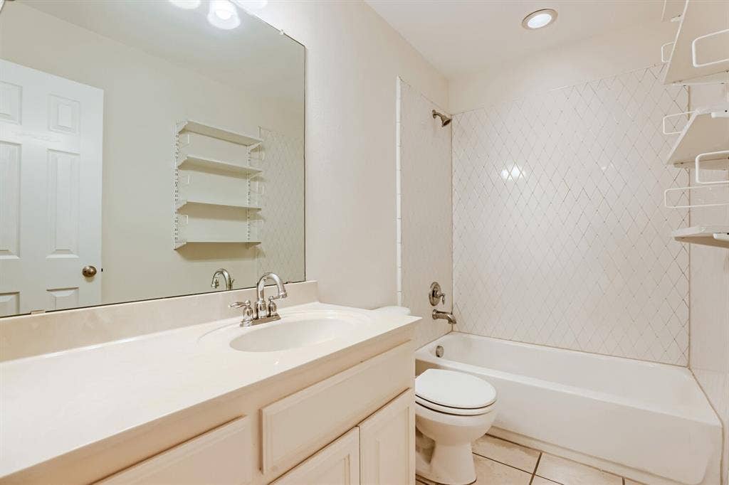 7013 Salem Court, Rowlett, TX 75089 Bathroom featuring a vanity with an integrated sink, large wall-mounted mirror, white cabinetry, a tub-shower combination with diamond-patterned tile surround, and tile flooring