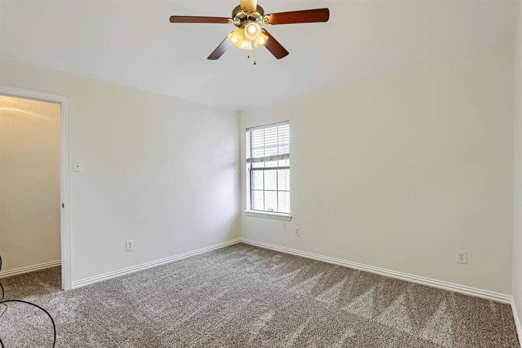 7013 Salem Court, Rowlett, TX 75089 Neutral interior featuring wall-to-wall carpeting, a ceiling fan with integrated lighting, and a window with horizontal blinds