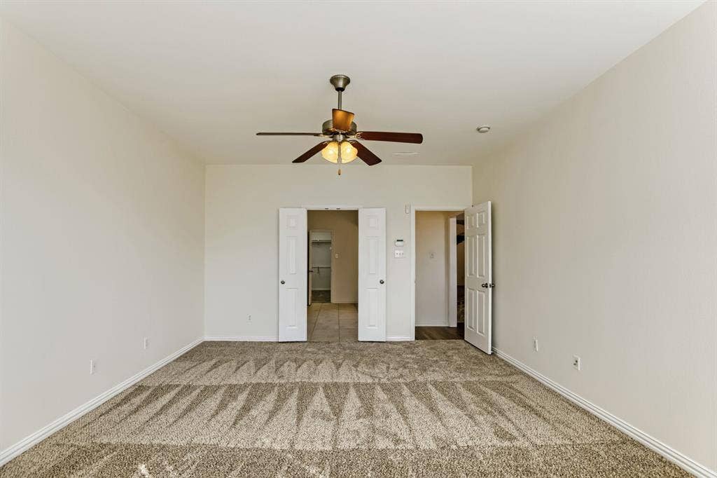 7013 Salem Court, Rowlett, TX 75089 Room featuring wall-to-wall carpeting, a ceiling fan with integrated lighting, and multiple interior paneled doors