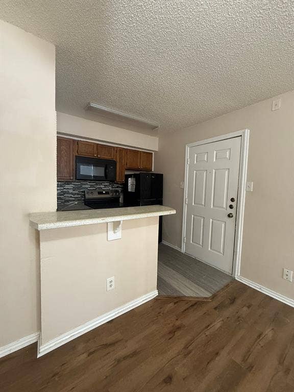 Kitchen featuring a breakfast bar with stone-finish countertop, wood-finish cabinetry, mosaic tile backsplash, and built-in microwave