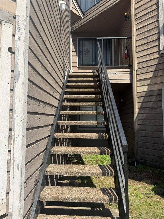 Exterior staircase with aggregate treads, black metal handrails, and lap siding