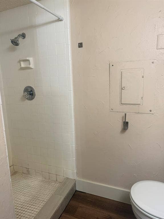 Walk-in shower enclosure with white tile surround, integrated soap dish, chrome shower head, chrome handle, and wood-finish flooring