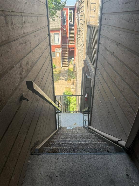 Exterior staircase featuring horizontal siding, metal handrails, and exposed aggregate concrete steps