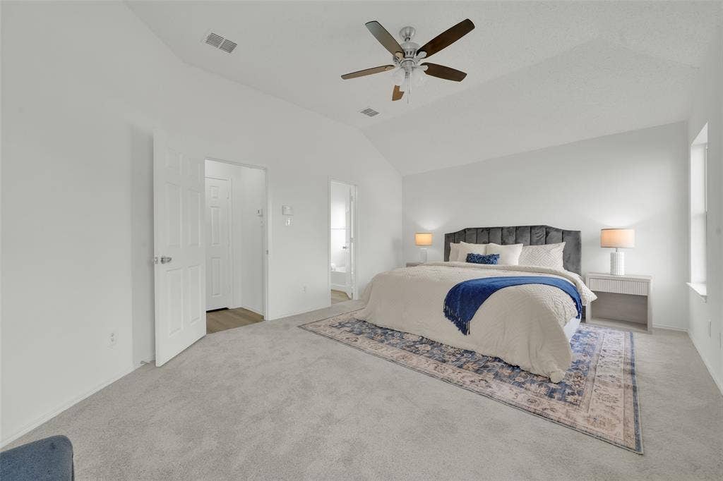 Vaulted ceilings, neutral carpeting, and a ceiling fan with integrated light fixture