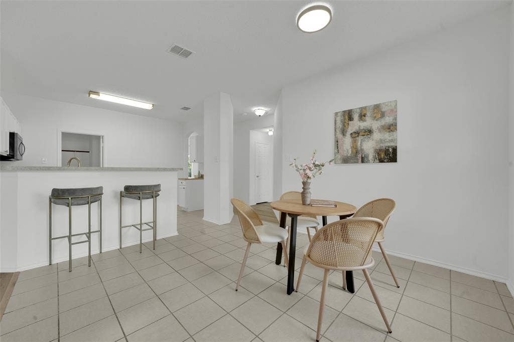 Neutral-toned ceramic tile flooring, breakfast bar with a solid surface countertop, and flush-mount lighting fixtures